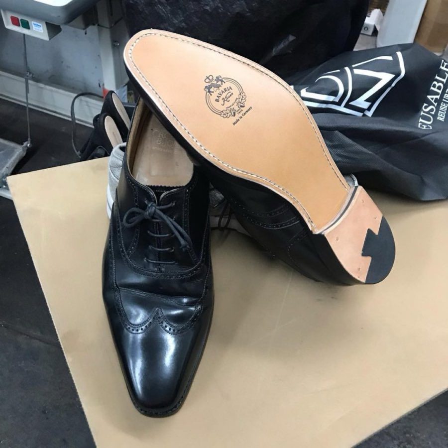 Black Gucci horsebit loafers, freshly resoled, resting soles-up on the shop's glass counter