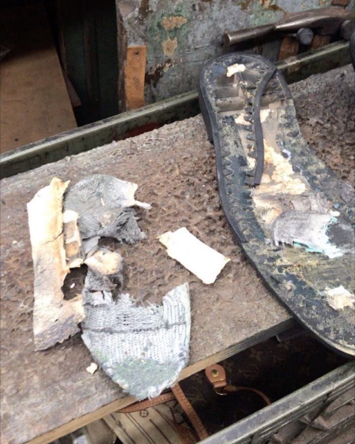 A worn sandal sole and insole material laid out on the workbench mid-repair