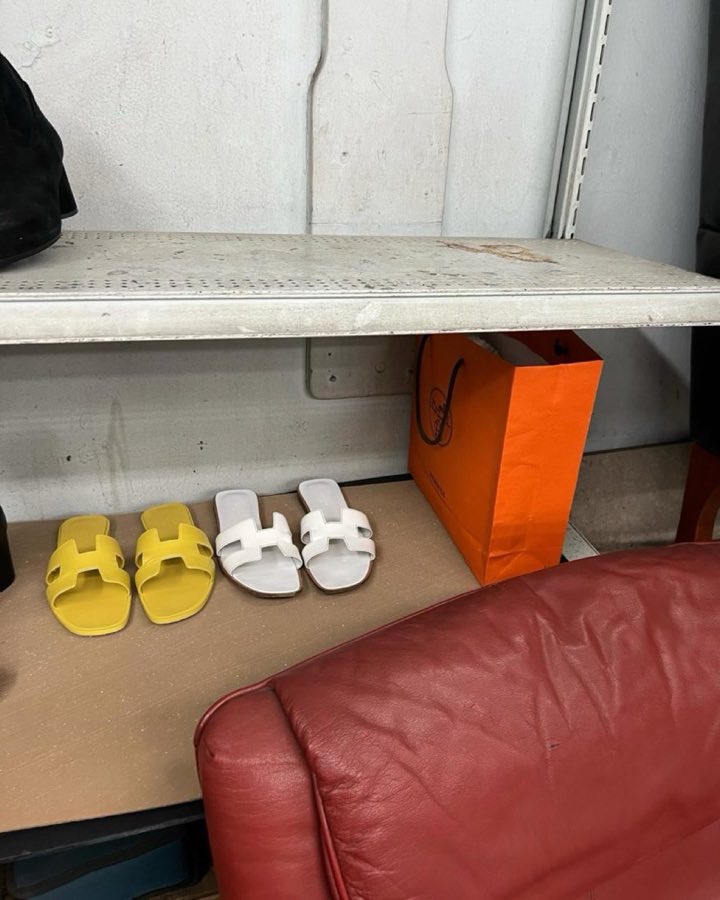 Yellow and white slide sandals and a designer shopping bag on a shelf in the shop