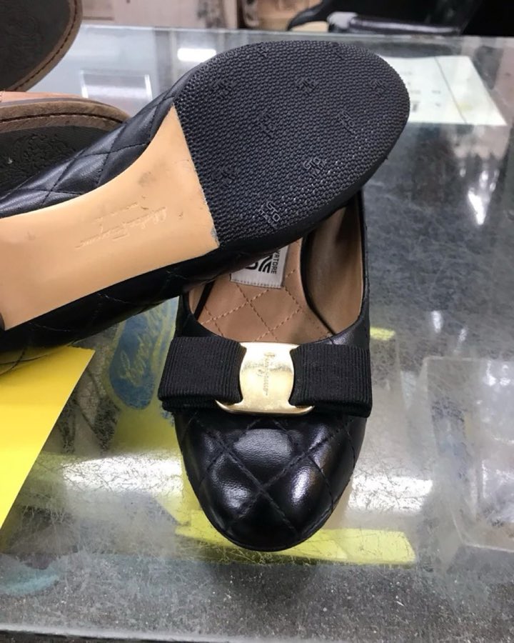 Studded black pointed-toe heels, resoled, resting soles-up on the counter