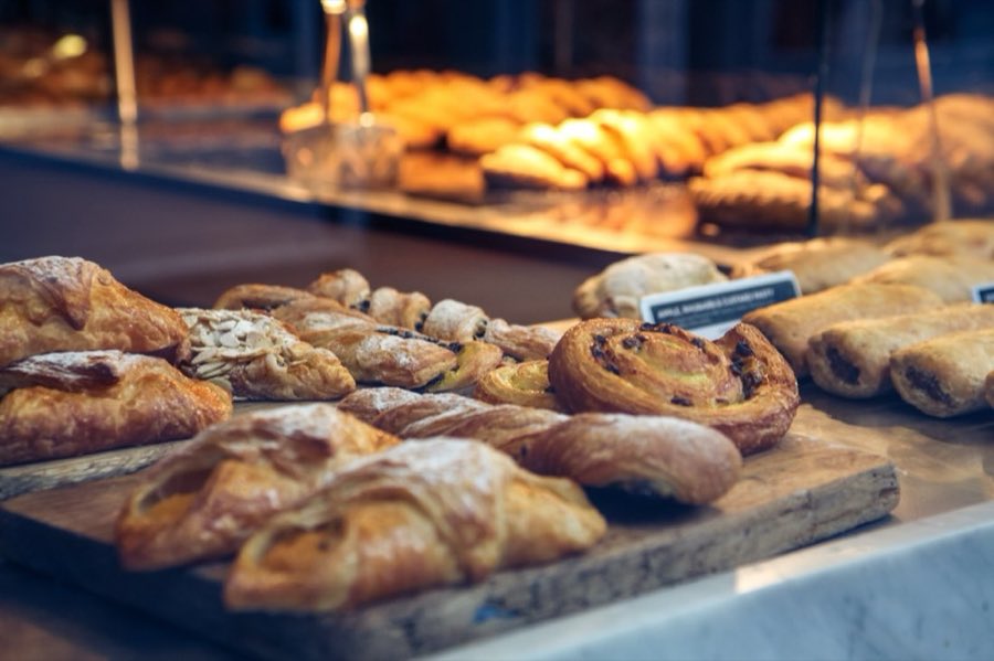 A baker's flour-dusted hands kneading and stretching dough on a wooden worktable