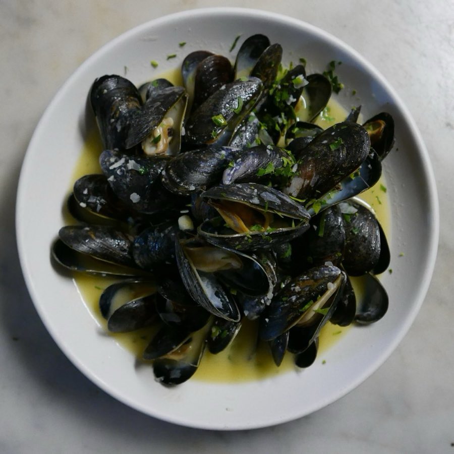 Mussels in white wine broth with a lemon wedge