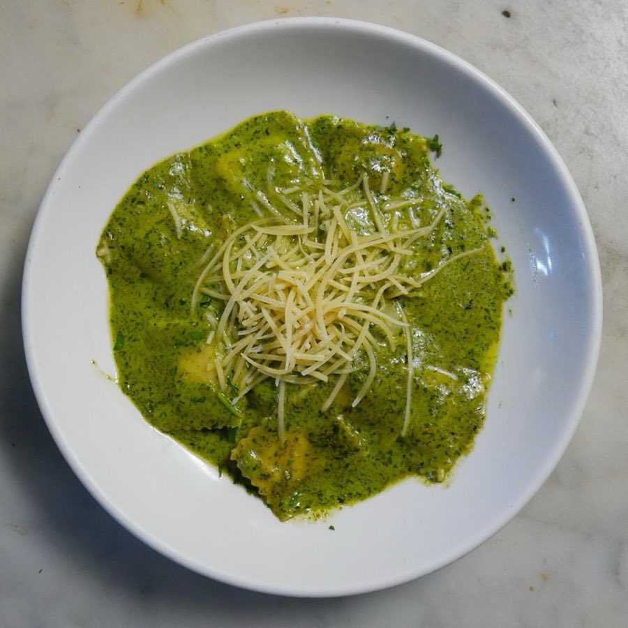 Pasta tossed in pesto and topped with shaved parmesan