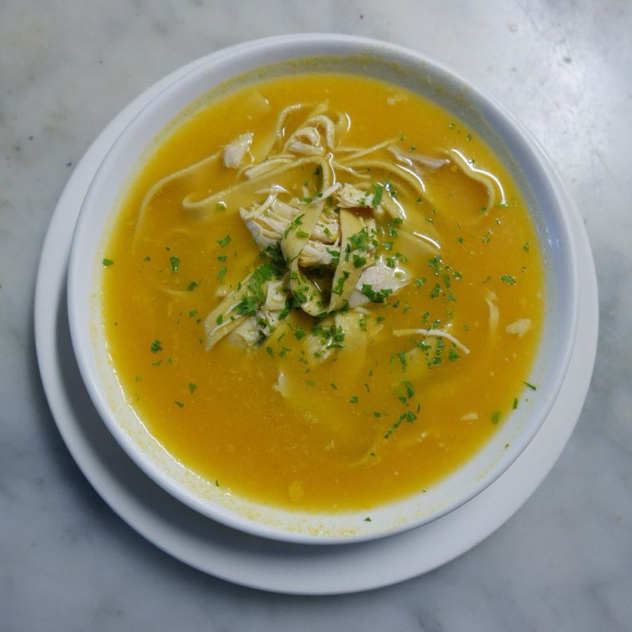 A bowl of seafood soup with a golden broth