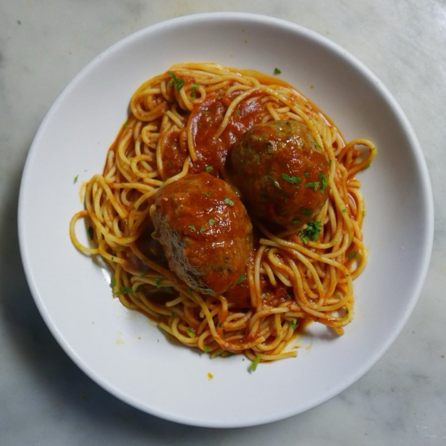 A plate of spaghetti and meatballs in red sauce, classic red-sauce Italian-American presentation