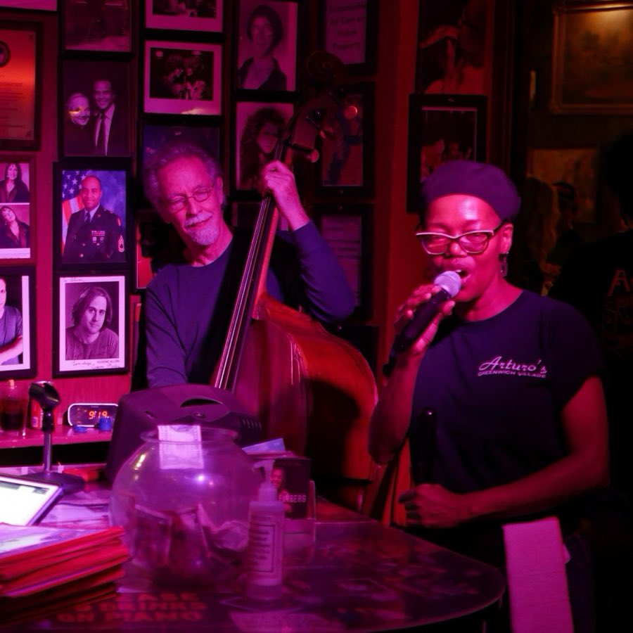 An upright bassist performing under warm red stage lighting