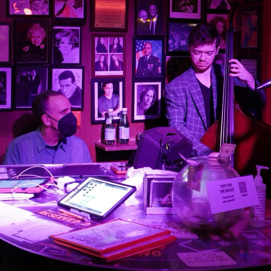 Two musicians performing together in front of the restaurant's wall of photographs