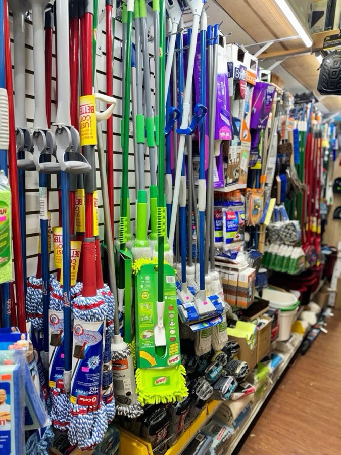 Aisle of mops, brooms, and cleaning tools hanging on display