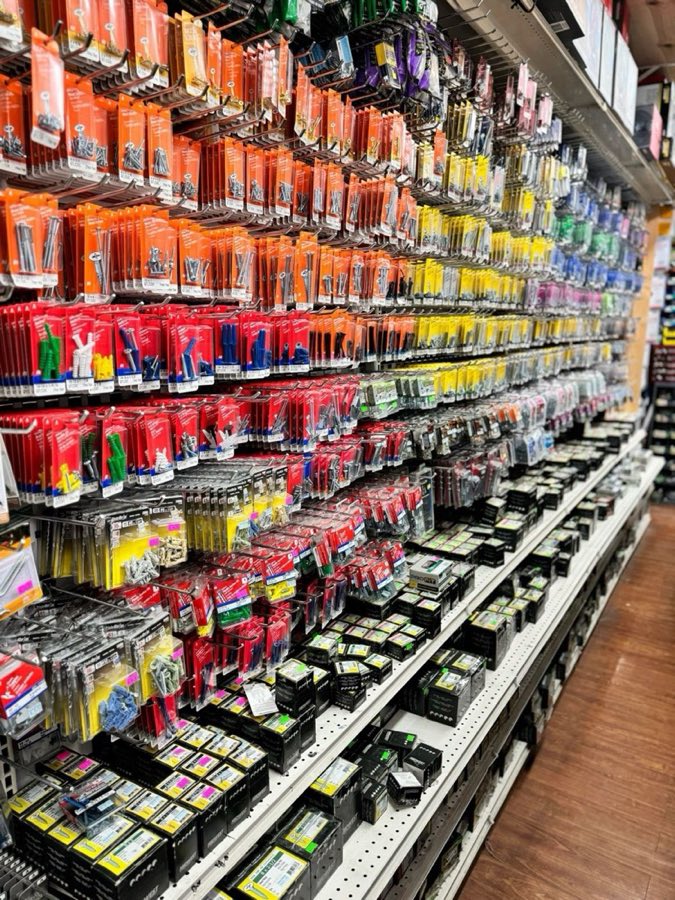 Wall of packaged fasteners, screws, drill bits, and wall anchors organized in color-coded blister packs at Beacon Hardware