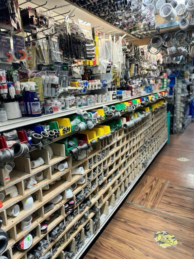 Wall of PVC elbows, sealants, and plumbing tools organized in wooden bins