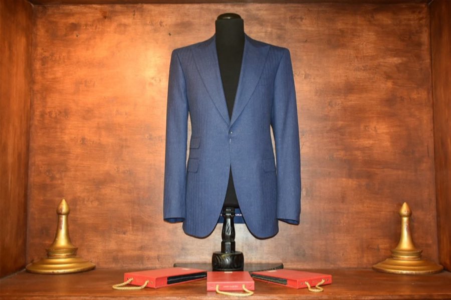 Blue tailored jacket on a mannequin with gold trophy accents on the shelf below