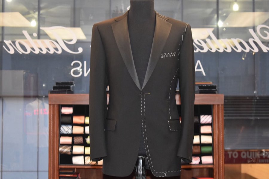 Navy shawl-collar jacket displayed on a mannequin against a deep red wall