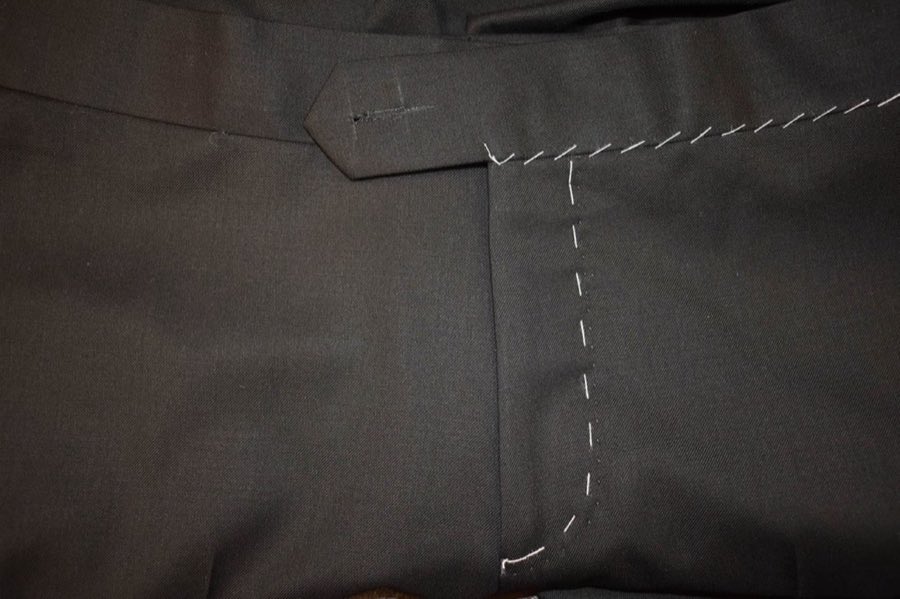 Interior of an unfinished black jacket showing hand-stitched canvas and lining under construction