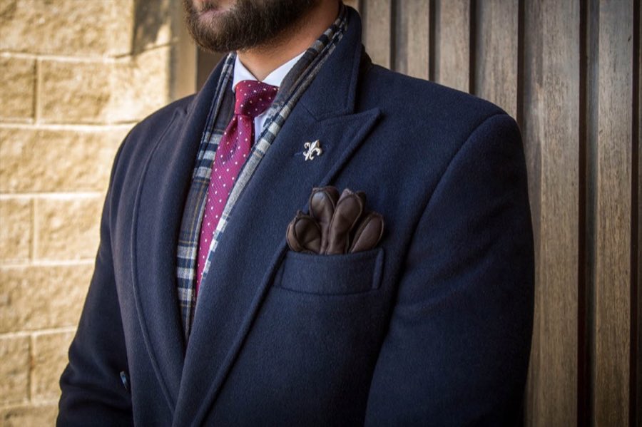 Man wearing a tailored navy suit with a pink pocket square and patterned tie