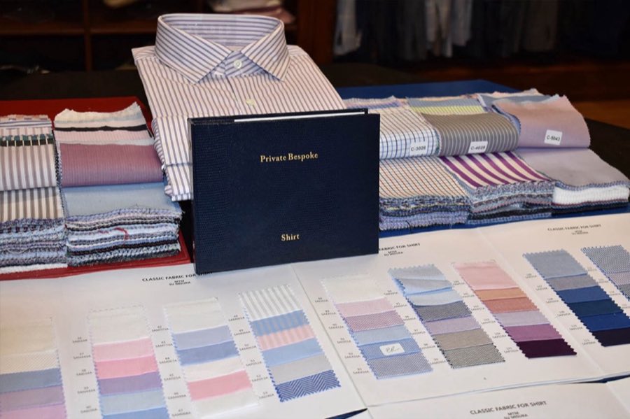 Folded custom shirt beside fabric swatch books and sample cards labeled Private Bespoke Shirt
