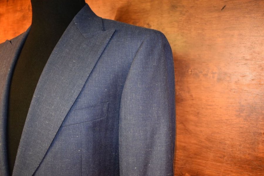 Tailor measuring a client's shoulders while they wear a checked jacket