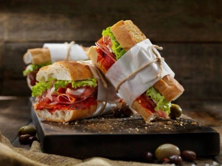 Editorial-style photograph of wrapped hero sandwiches, used here as decorative texture