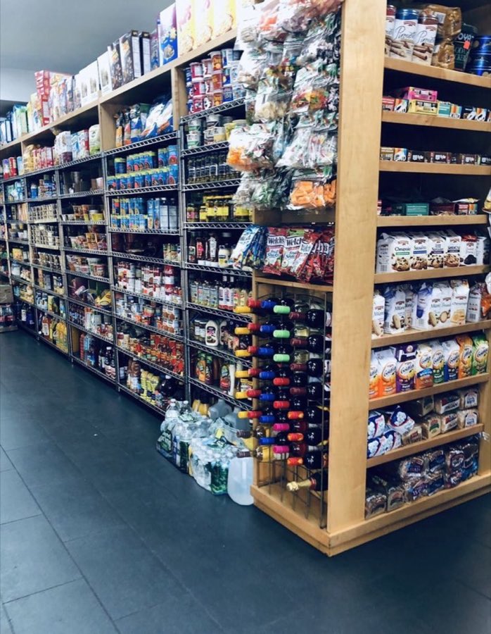 Interior of Don Juan Grocery: wood shelving stocked with cereal, cookies, canned goods, wine bottles, and bottled water