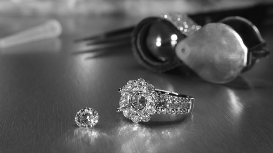 A loose diamond and an unset ring mounting on a jeweler's workbench