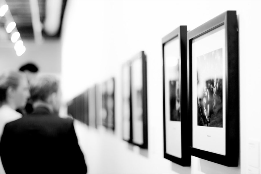 A row of framed black-and-white photographs displayed along a gallery wall