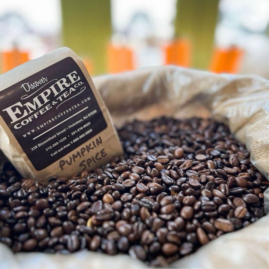 A kraft-paper Empire Coffee & Tea Co. bag labeled Pumpkin Spice, resting in an open burlap sack of whole roasted coffee beans