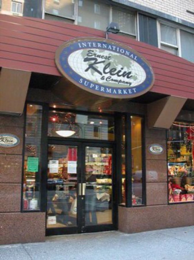 Ernest Klein & Company storefront on 6th Avenue, with burgundy awning and the oval navy-and-red Ernest Klein & Company sign over glass double doors
