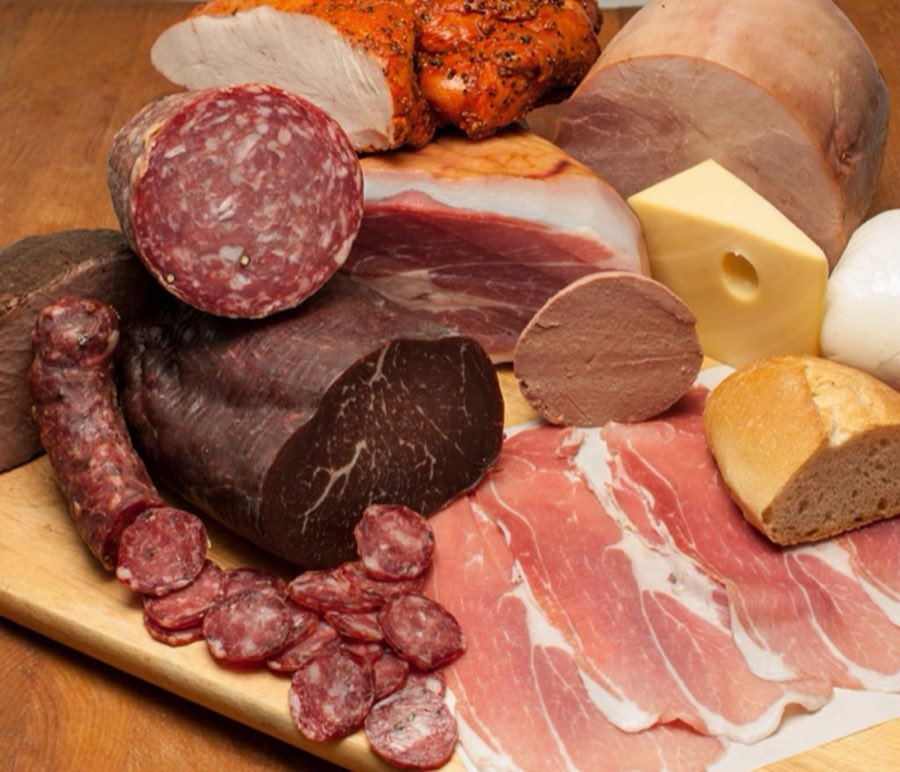 A deli spread of salami, prosciutto, mortadella, cheese, mozzarella, and bread on a wooden board