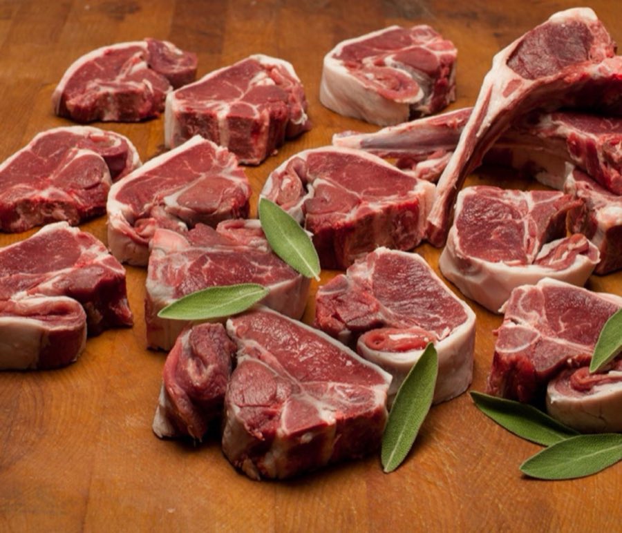 Raw lamb chops and cuts with sage leaves on a wooden butcher block