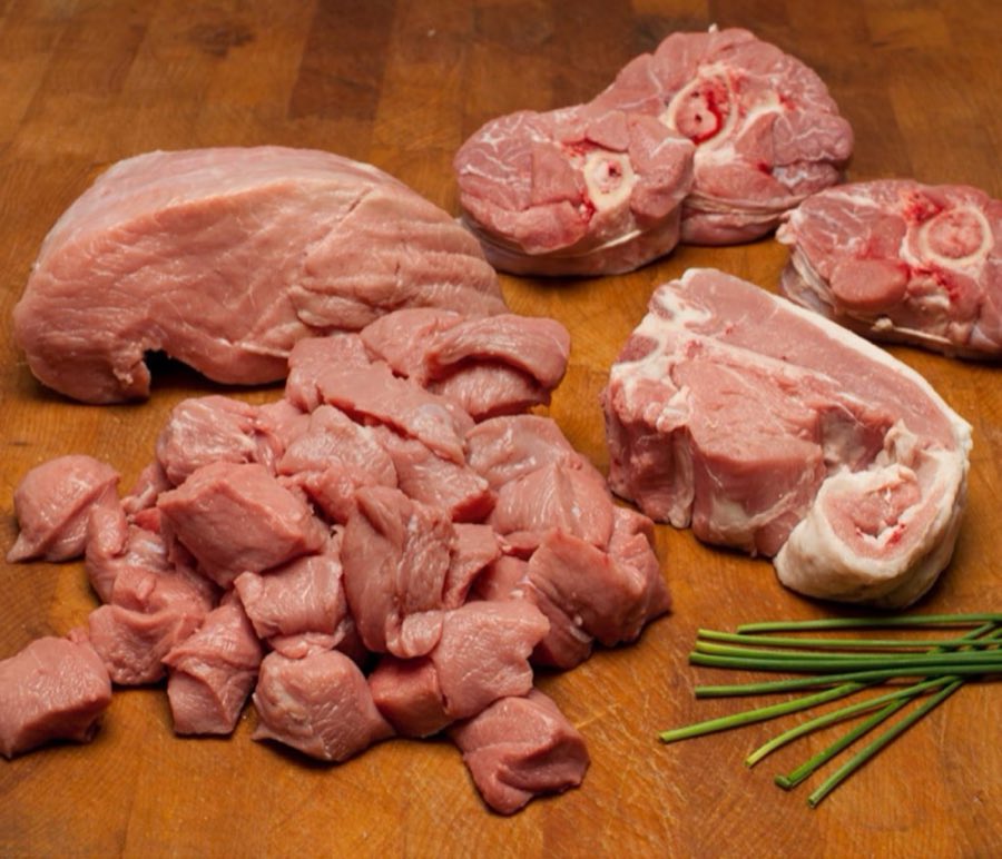 Raw veal shanks, cutlet, and chops with fresh chives on a wooden butcher block