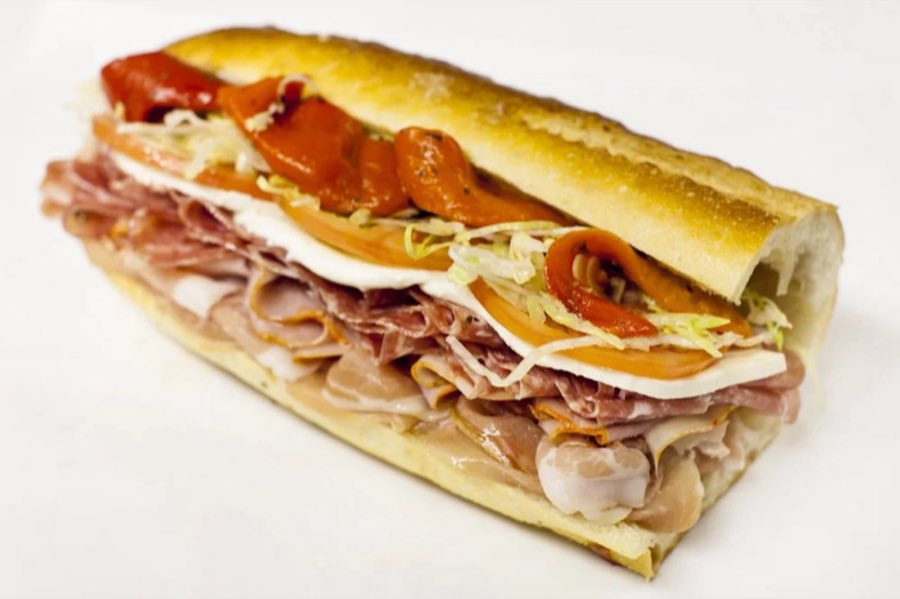 The Italian hero sandwich piled with prosciutto, ham, mozzarella, roasted red peppers, shredded lettuce, and tomato on a toasted hero roll