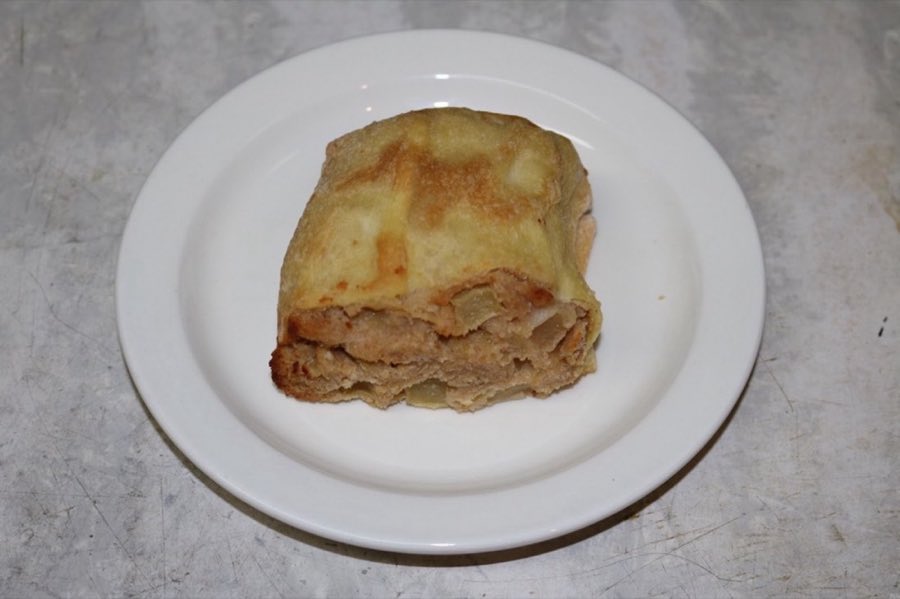 A baked apple strudel-style knish pastry, on a white plate