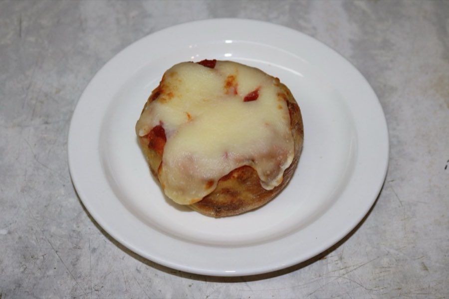 A round knish topped with tomato sauce and melted mozzarella, on a white plate