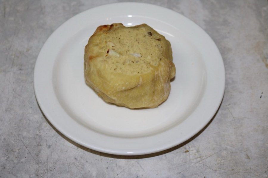 A single round baked potato knish on a white plate