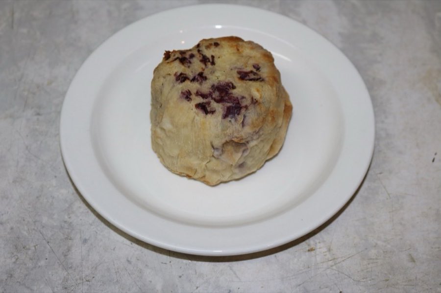 A round baked knish with red cabbage filling visible at the edge, on a white plate