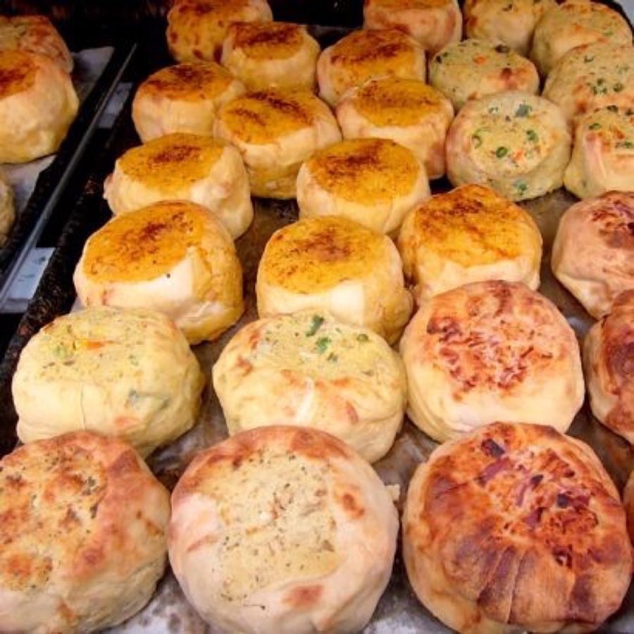 An overhead view of a boxed assortment of baked knishes with different toppings, ready for nationwide shipping