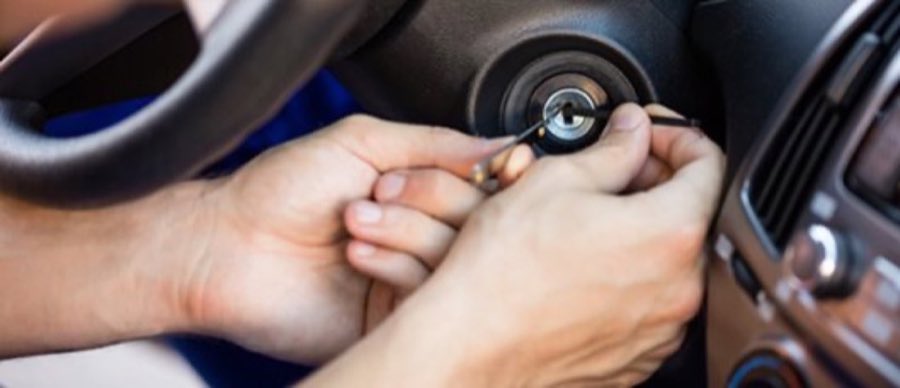Close-up of hands using a key tool to work on a car ignition and steering column