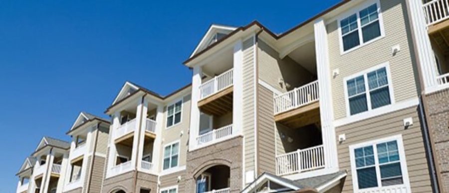 Exterior of a multi-story building with balconies, photographed against a blue sky