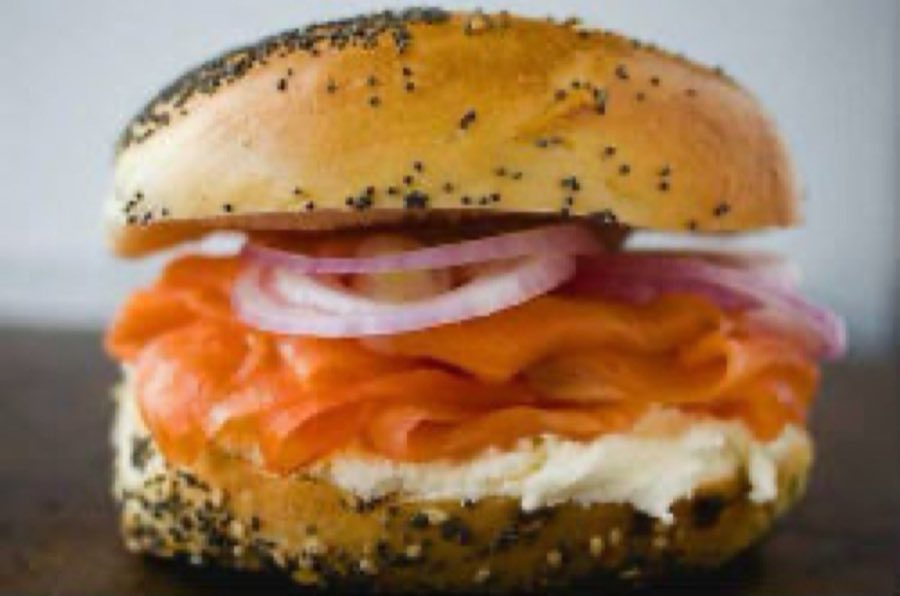An everything bagel filled with cream cheese, folds of orange lox, and rings of red onion