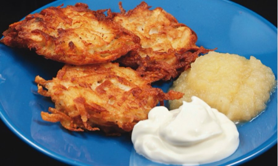 Three golden potato latkes on a blue plate with applesauce and a dollop of sour cream