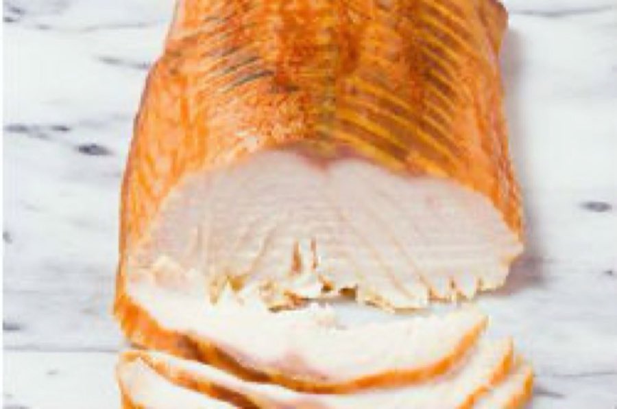 A whole side of smoked salmon on white marble, sliced to show its pink flesh