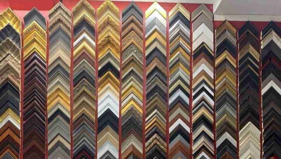 Close-up of nine framing corner samples fanned out, showing walnut, gilt, black, and hand-carved finishes