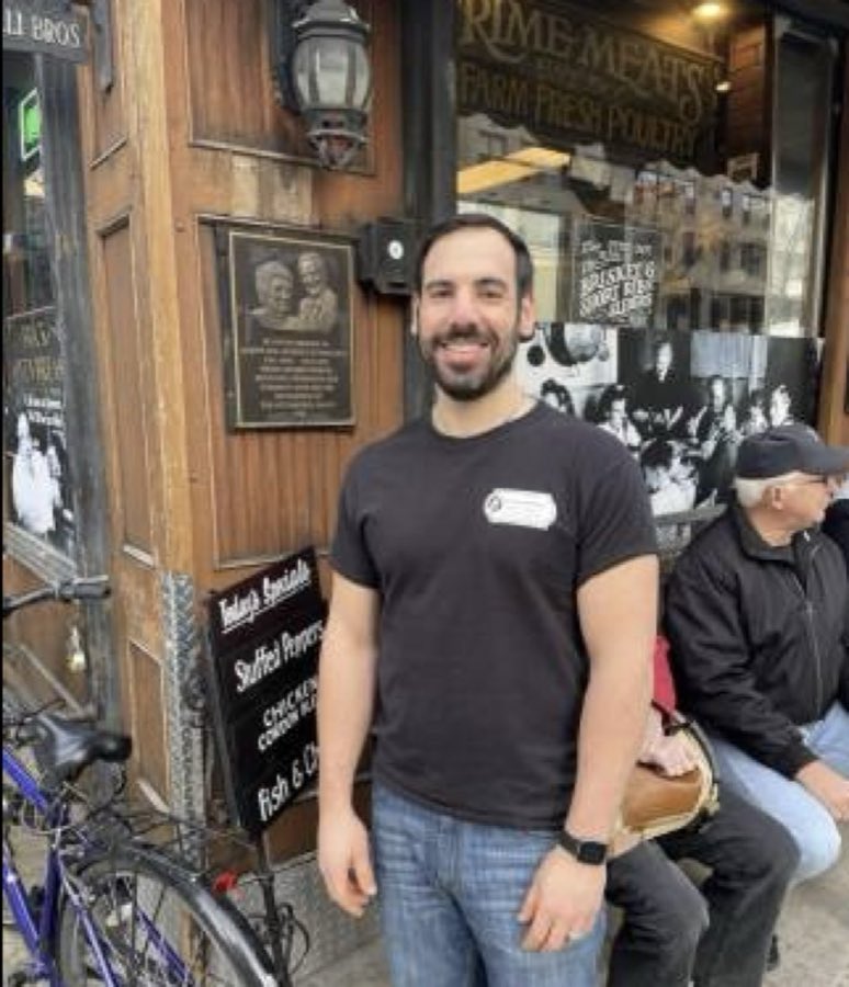 The Prime Meats and Farm Fresh Poultry storefront sign above a framed vintage photograph of the Ottomanelli family at the table, with a basket of pasta