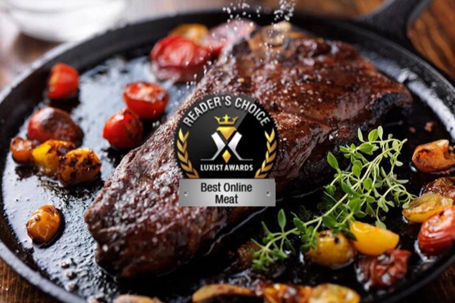 A seared steak in a cast-iron pan with a Reader's Choice Best Online Meat award badge