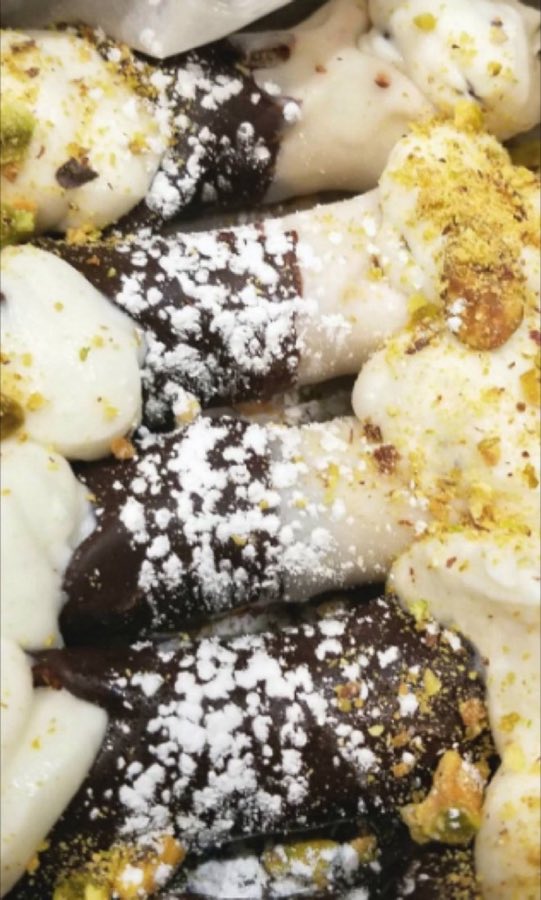 A chocolate-dipped cannoli filled with ricotta cream and chocolate chips