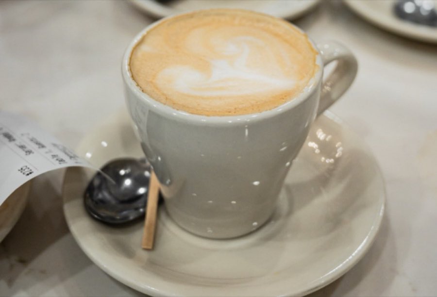 A cappuccino with heart-shaped latte art in a white cup on a saucer