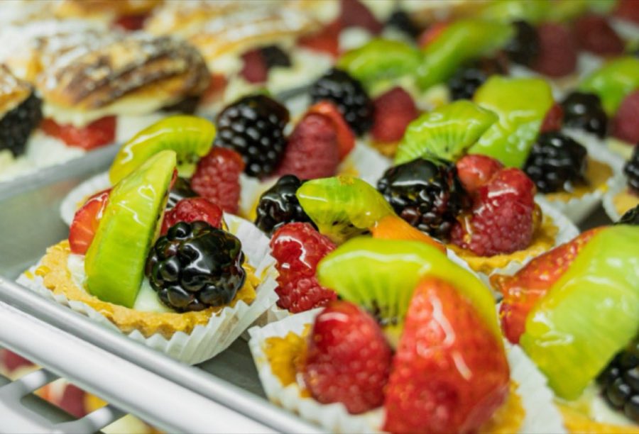 A tray of glazed miniature fruit tarts topped with kiwi, strawberry, blackberry and raspberry