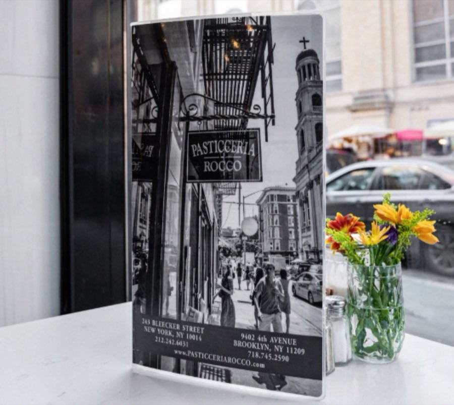 Rocco&rsquo;s menu card on a marble café table, printed with a black-and-white photo of the Bleecker Street storefront and both shop addresses
