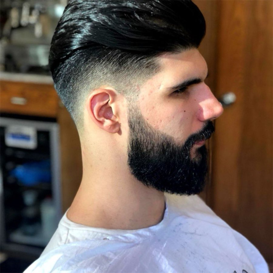Close profile view of a client's freshly cut fade and groomed beard at the shop