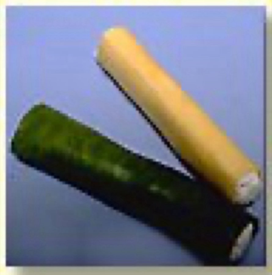 Two rolled manicotti tubes, one green and one cream, on a blue background