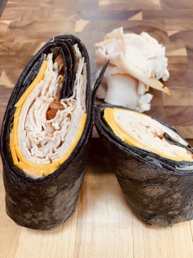 A wrap sliced open showing fresh vegetables and greens